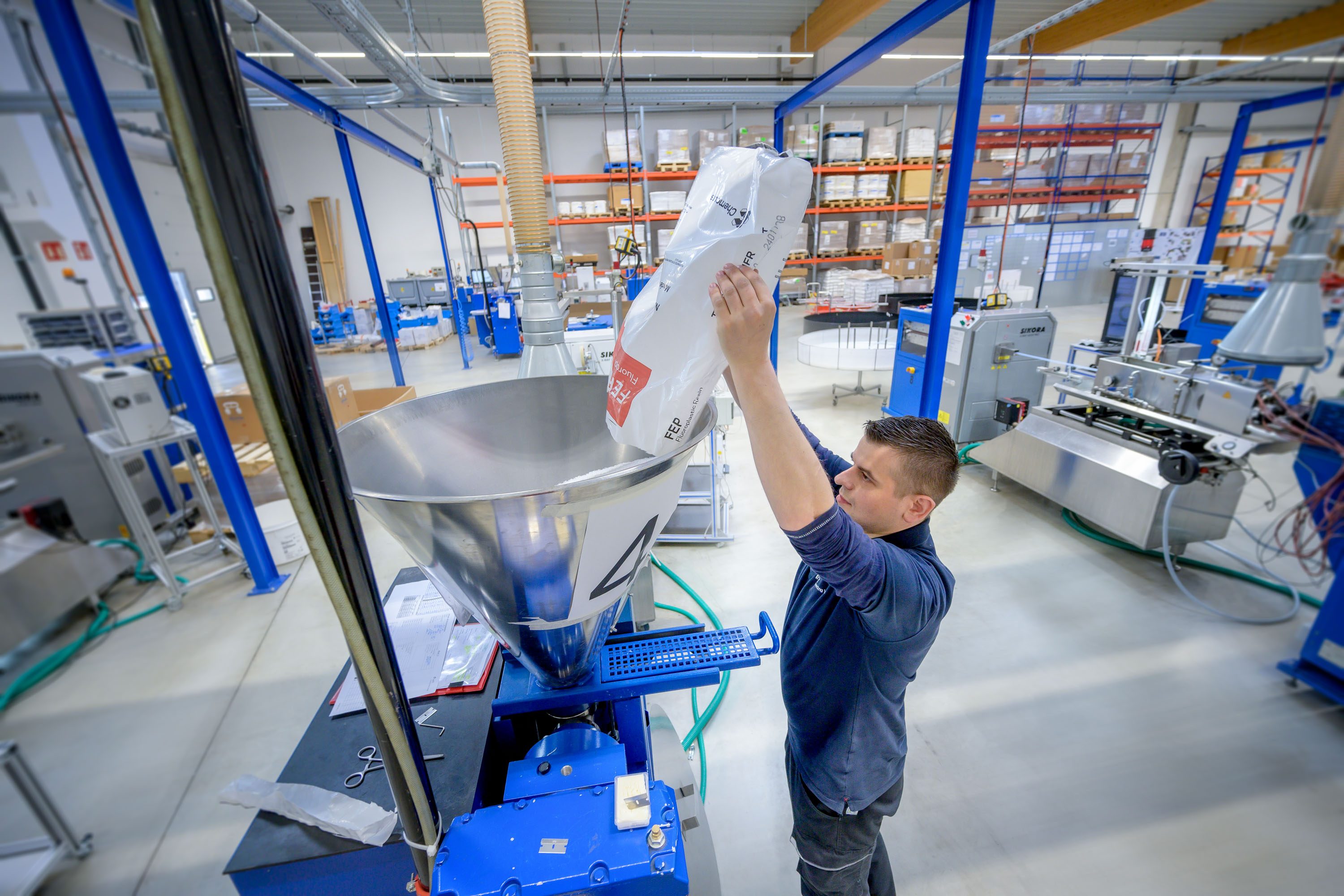 Photo from APT production: employee filling material into the extruder