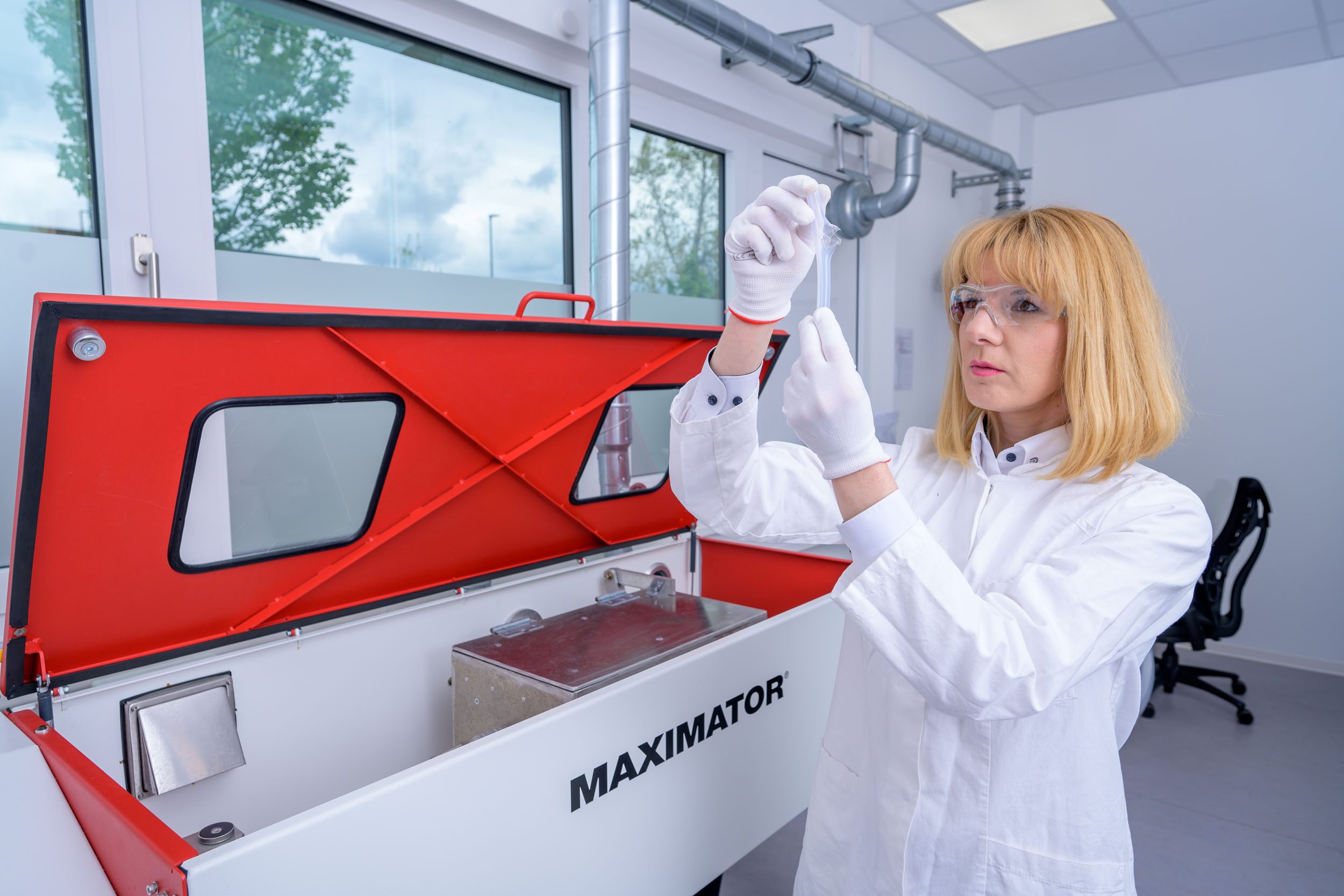 Picture: a blonde-haired employee from APT's quality assurance department holds a semicon plastic tube in her hand and checks it