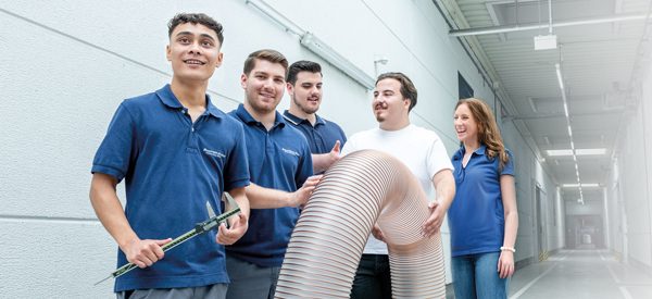 Five trainees smile and hold a hose
