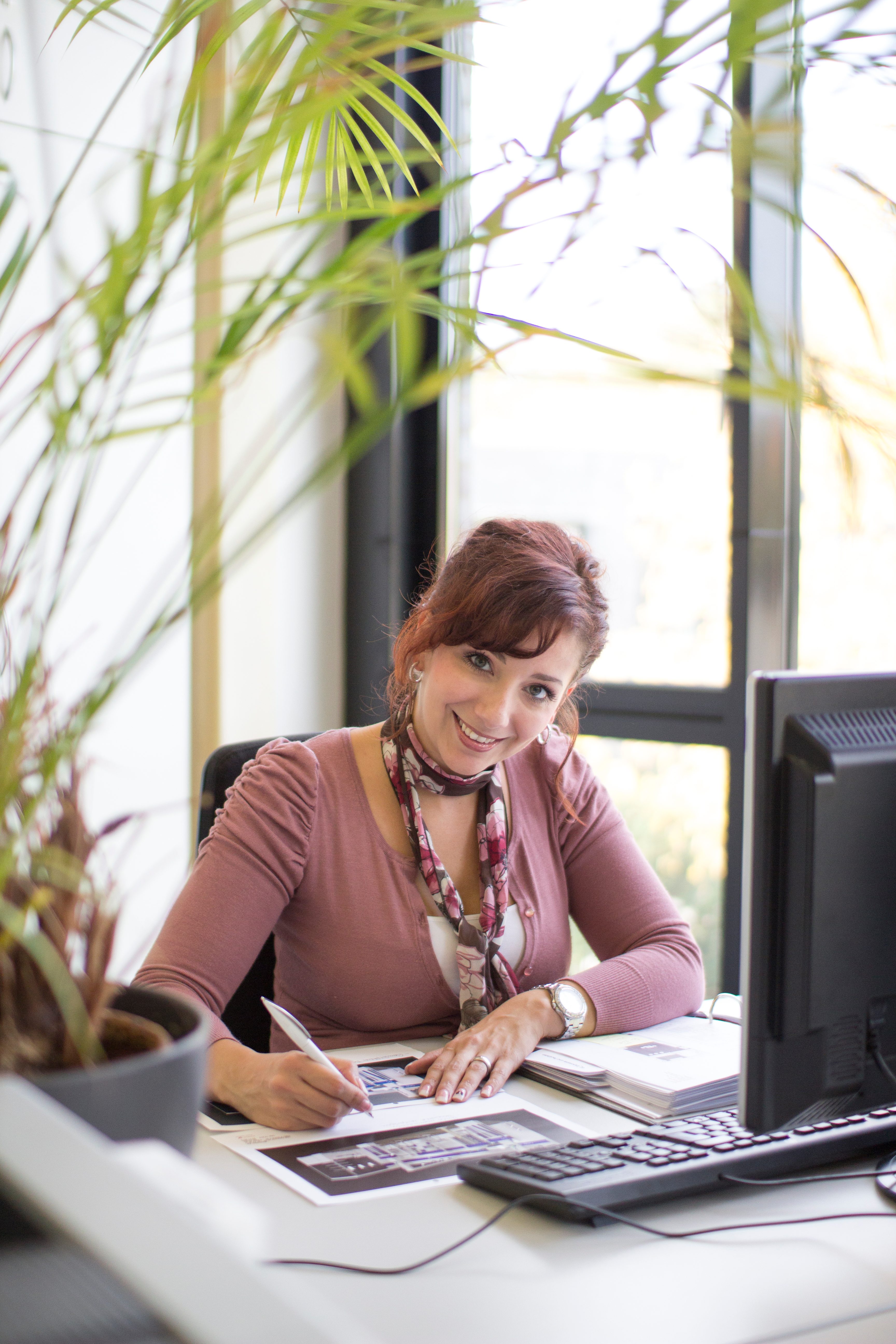 Frau sitzt vor Schreibtisch und lächelt