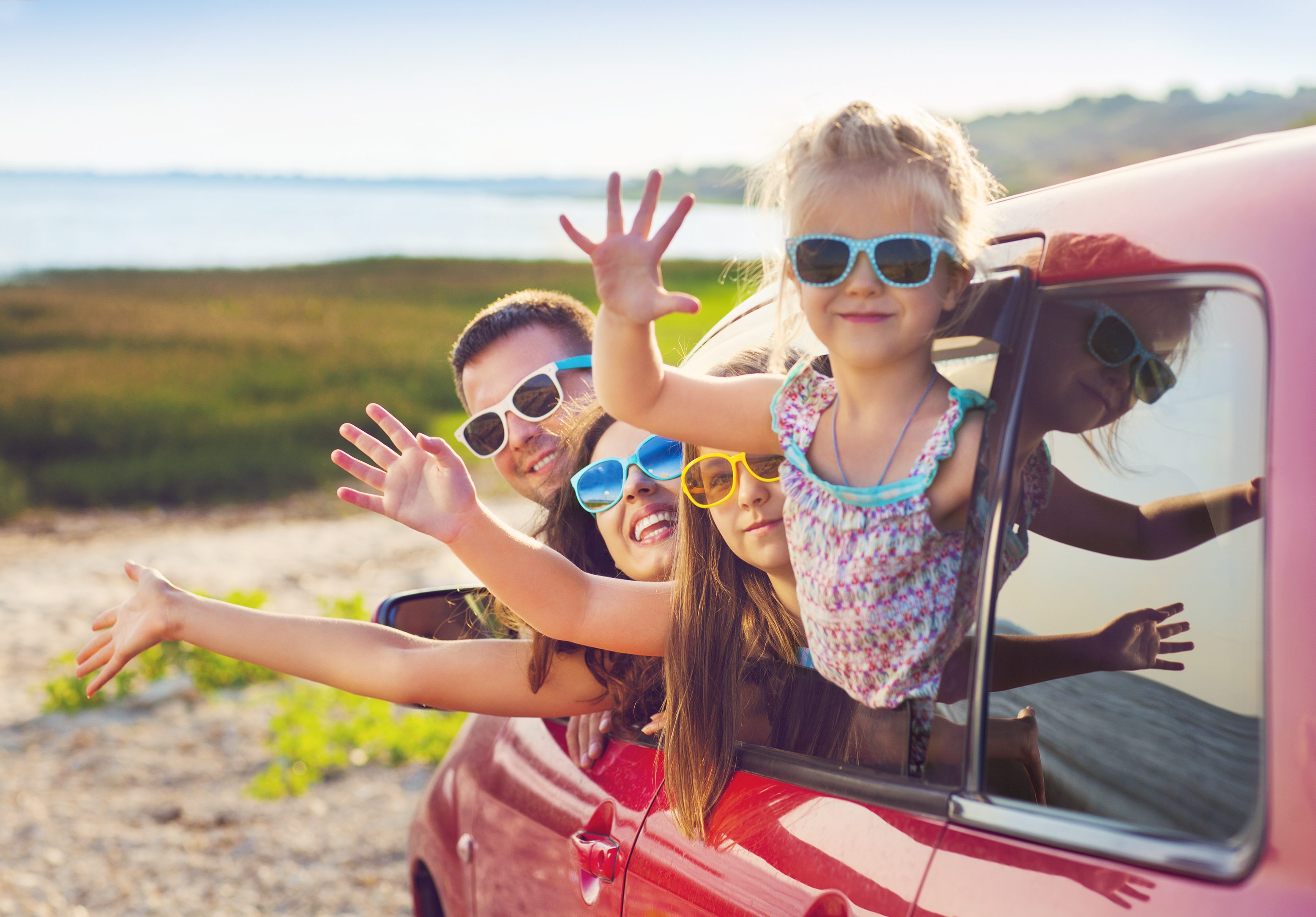 Masterflex Group Urlaubsstimmungsbild: Fröhliche Familie winkend im Auto