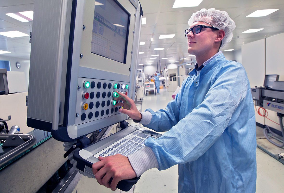 Masterflex Group, Novoplast: Neue Produktionsanlage mit Bedienpanel im neu errichteten Reinraum von Novoplast in Halberstadt, mit einem Mitarbeiter aus dem Bereich Medizintechnik der die Maschine bedient