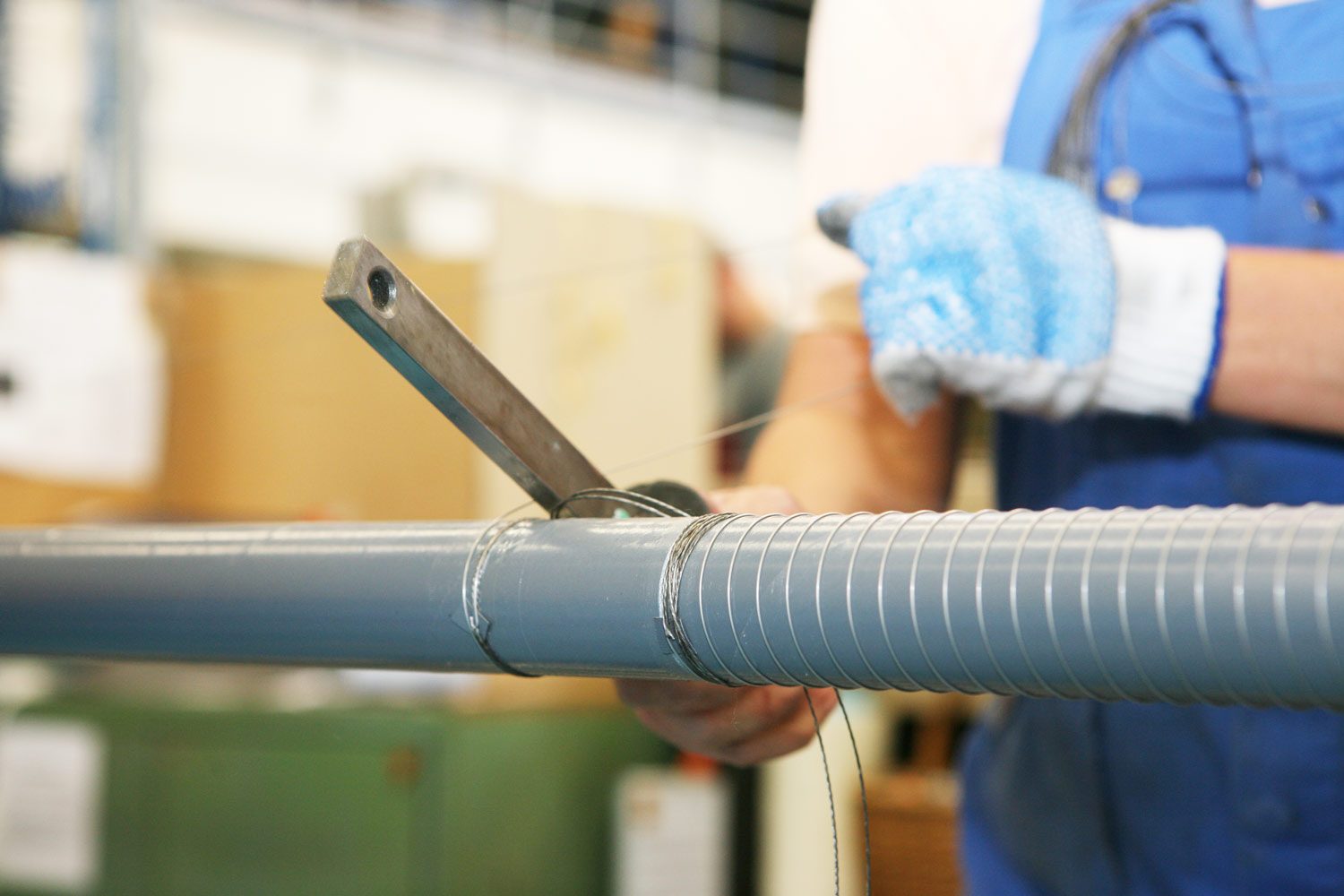 Ein Mitarbeiter der Matzen und Timm umwickelt einen Schlauch mit Draht.
