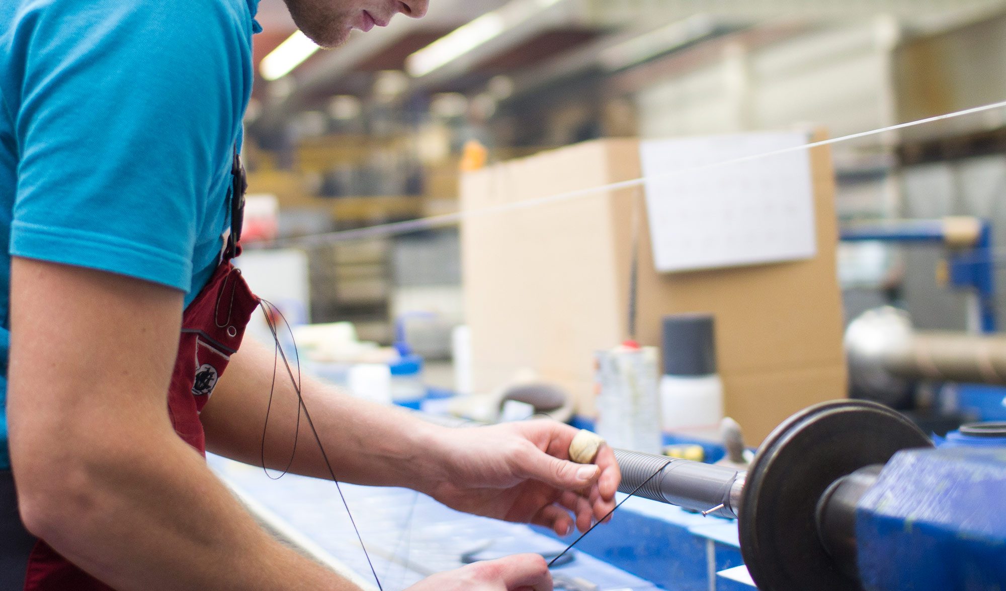 Ein Mitarbeiter der Matzen und Timm umwickelt einen Schlauch mit einem Faden. 