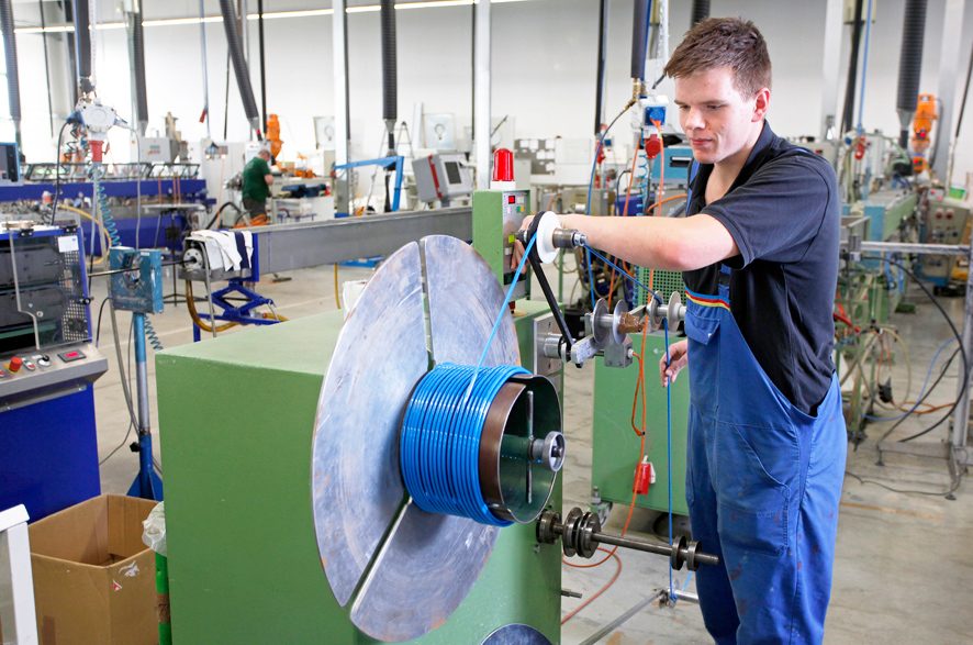 A Novoplast employee produces a blue smooth hose on a machine.