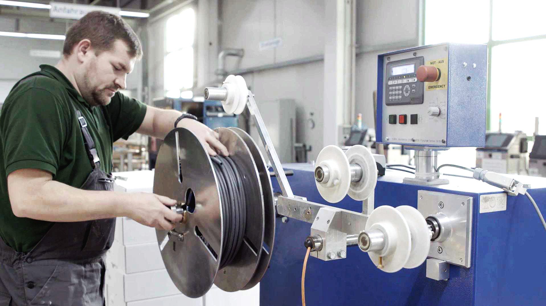 A Novoplast employee produces a black smooth hose on a machine.