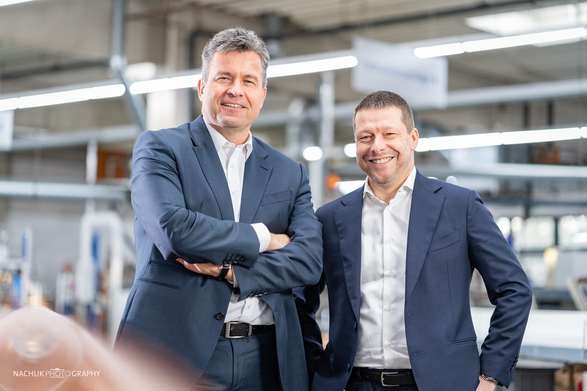The members of the Executive Board stand smiling in a production hall at Masterflex SE.