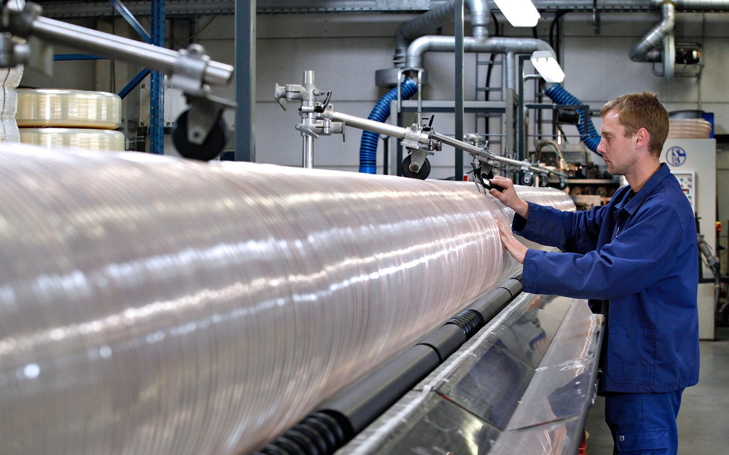 A Masterflex employee stands at a machine and monitors the production of a hose. 