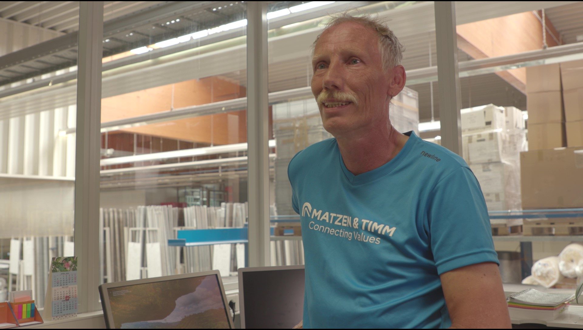 A smiling employee in the production rooms of Matzen & Timm during an interview about working with handicapped people.