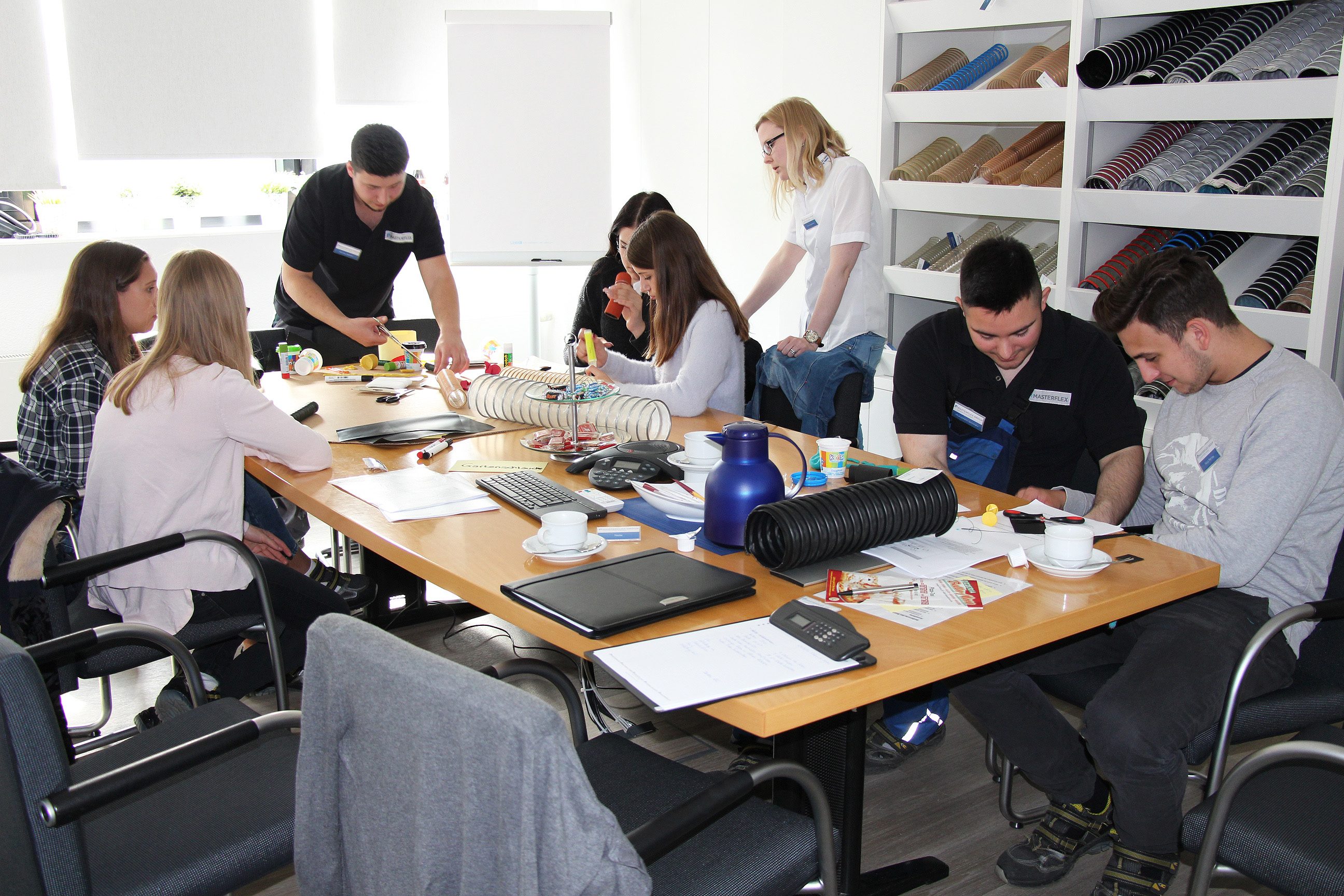 The development engineer with a group of pupils working on a hose in a workshop. 