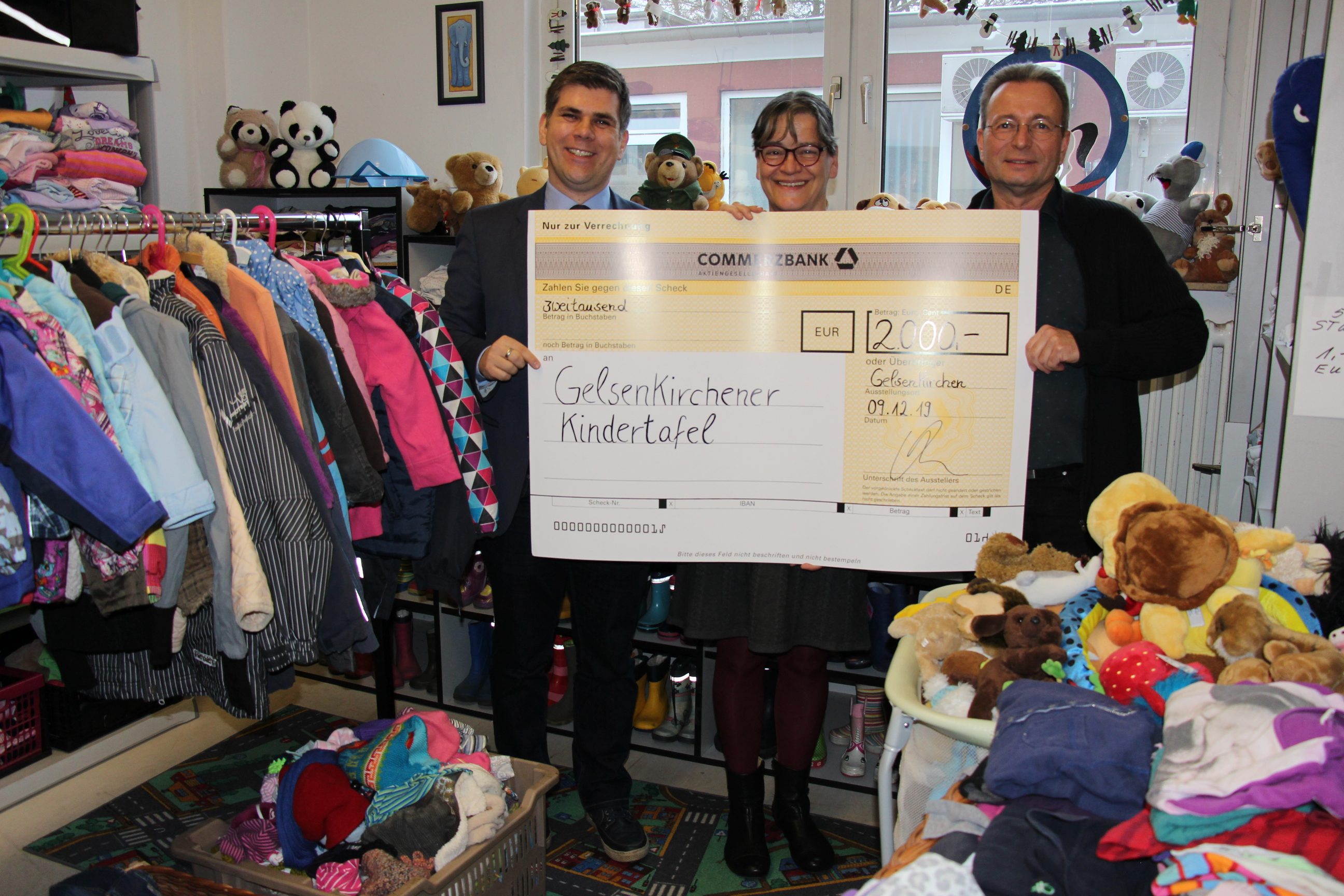 Mr. Mettge hands over a check from the Masterflex Group to two employees of the Gelsenkirchener Kindertafel with a smile. 
