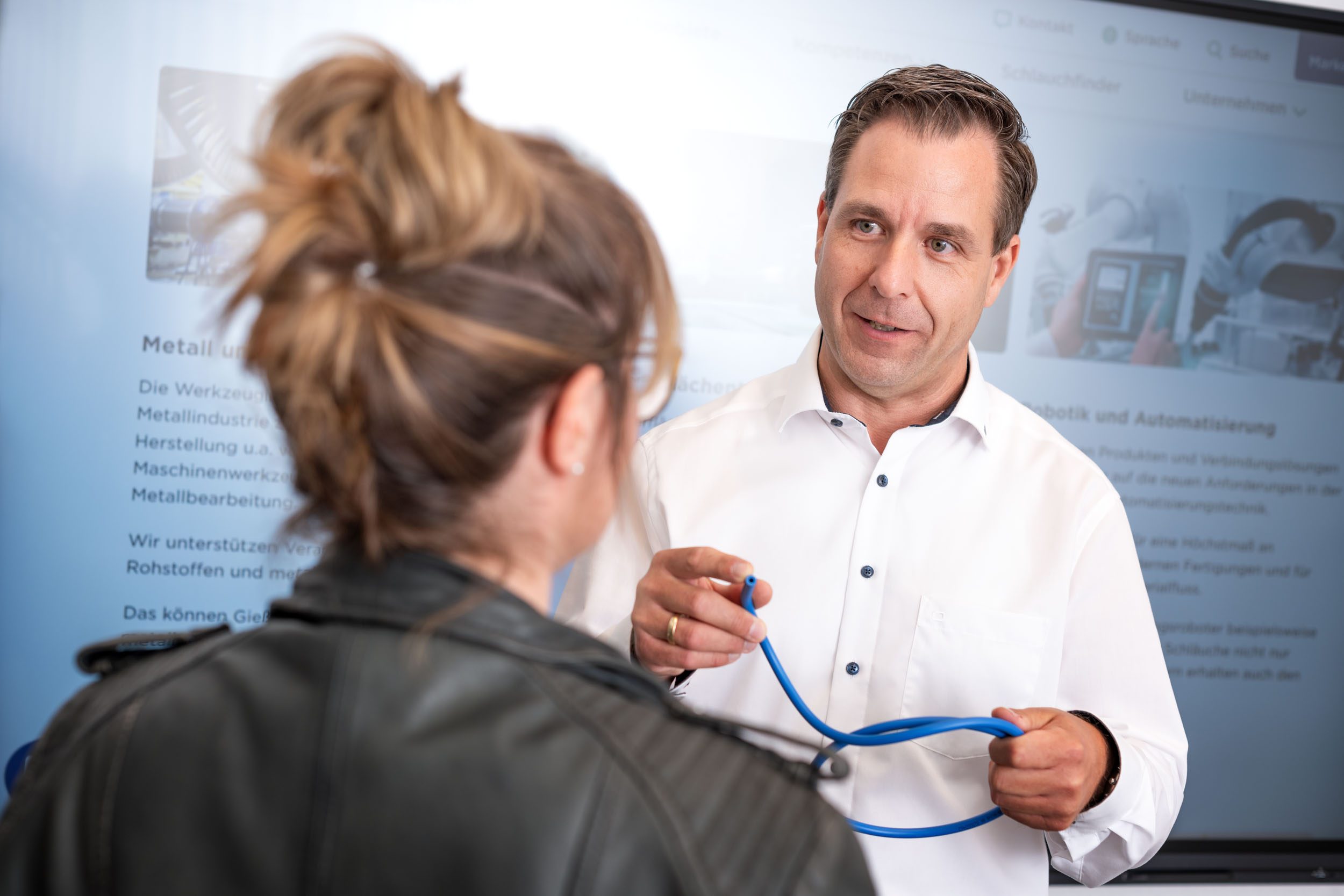 Mitarbeiter präsentiert Robotikschlauch einer Mitarbeiterin